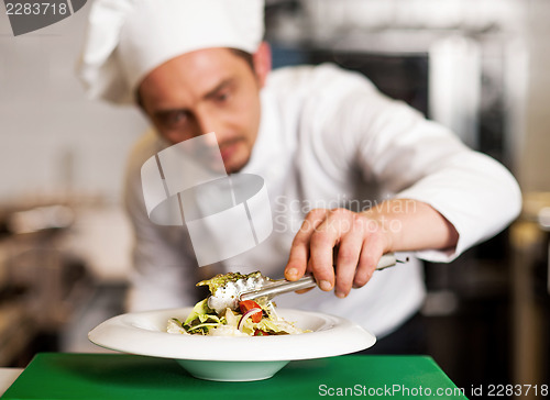 Image of A chef arranging tossed salad in a white bowl
