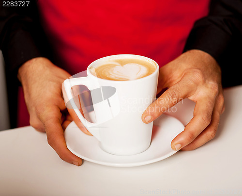 Image of Hands of waiter serving a cup of cappucino