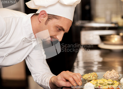 Image of Satisfied chef analyzing dish before serving