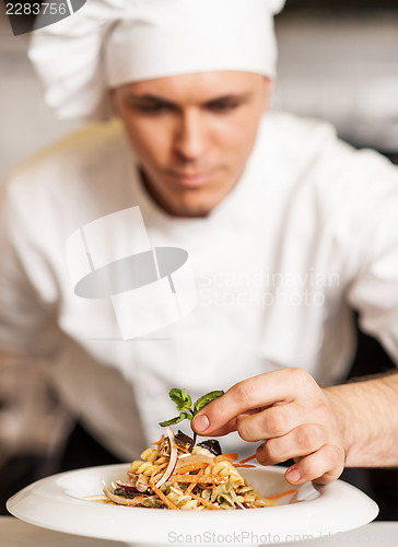 Image of Chef decorating pasta salad with herbal leaves