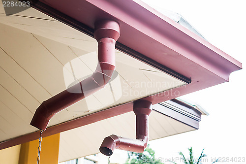 Image of Corner of house with rain gutters on sky background 