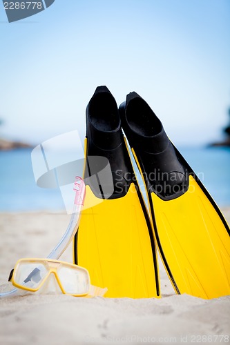 Image of yellow fins and snorkelling mask on beach in summer