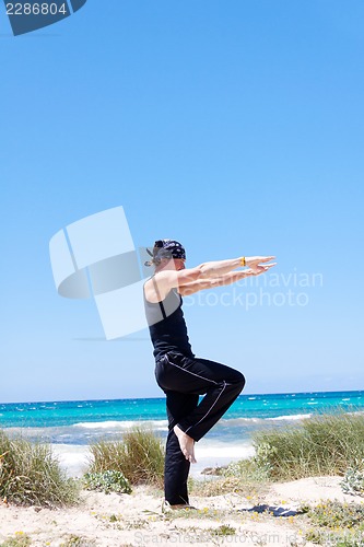 Image of man doing pilates exercises on beach in summer