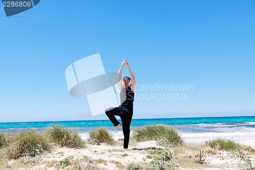 Image of man doing pilates exercises on beach in summer