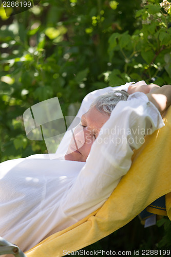 Image of Senior woman sleeping on lounger