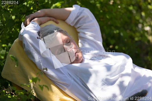 Image of Mature woman sleeping on lounger