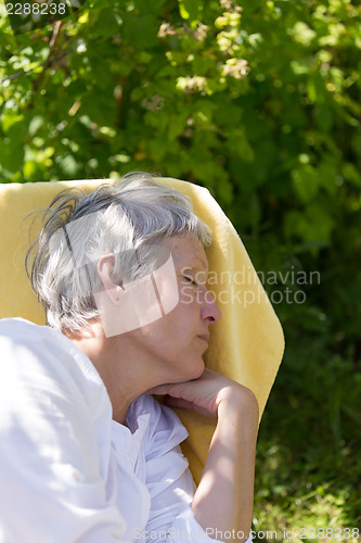 Image of Aged woman sleeping on lounger