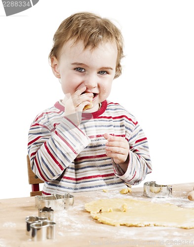 Image of happy young child nibbling dough in white background