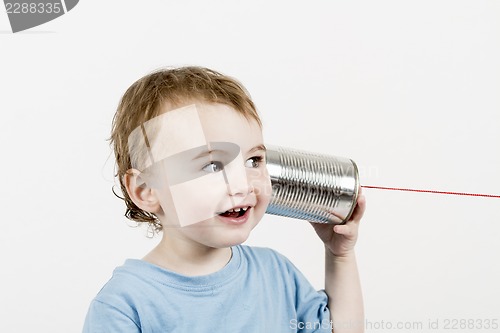 Image of friendly child listening to tin can phone