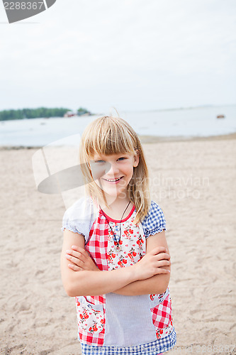 Image of Smiling young girl at beach with arms folded