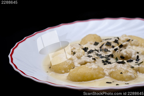 Image of italian gnocchi with four cheese sauce isolated on black