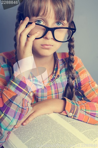 Image of serious little girl in glasses with a book