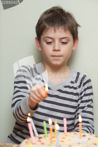 Image of A boy lights candles on cake