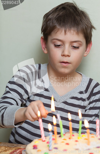 Image of A boy lights candles on cake