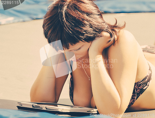 Image of busty woman with swimsuit reading news on tablet