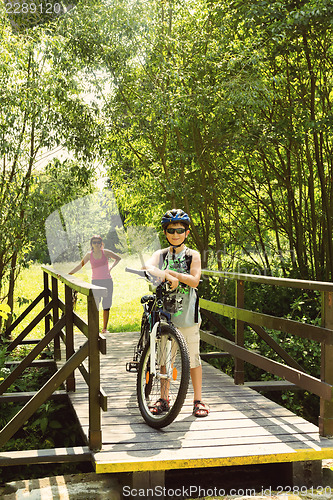 Image of teenager relaxing on a bike trip on wooden bridge