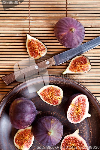 Image of  plate with fresh figs and old knife on straw background