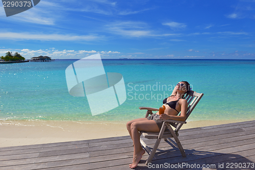 Image of Beautiful young woman with a drink by the sea