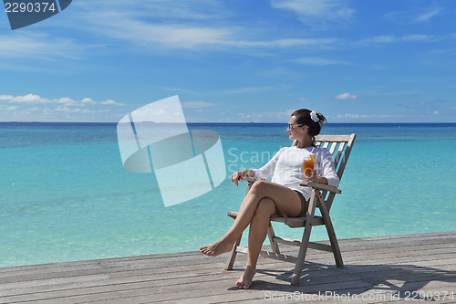 Image of Beautiful young woman with a drink by the sea