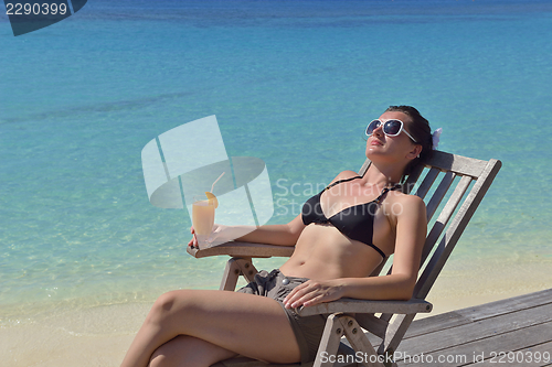 Image of Beautiful young woman with a drink by the sea