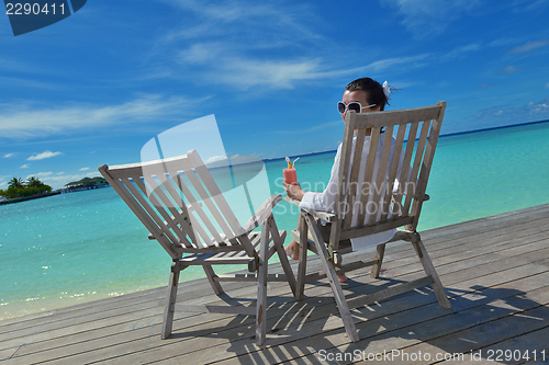 Image of Beautiful young woman with a drink by the sea