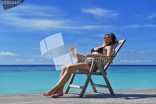 Image of Beautiful young woman with a drink by the sea