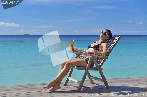 Image of Beautiful young woman with a drink by the sea