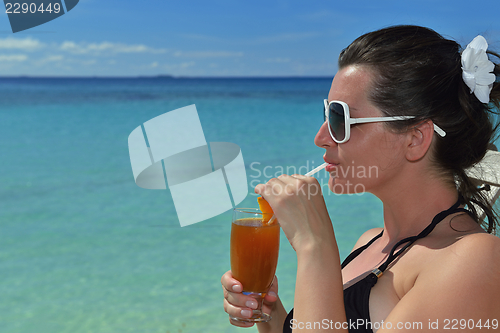 Image of Beautiful young woman with a drink by the sea