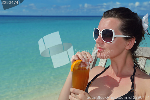 Image of Beautiful young woman with a drink by the sea