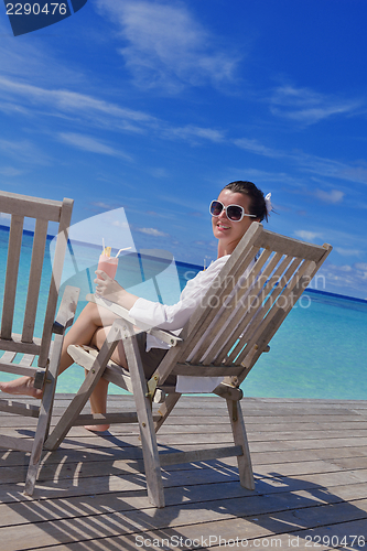 Image of Beautiful young woman with a drink by the sea