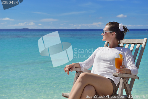 Image of Beautiful young woman with a drink by the sea