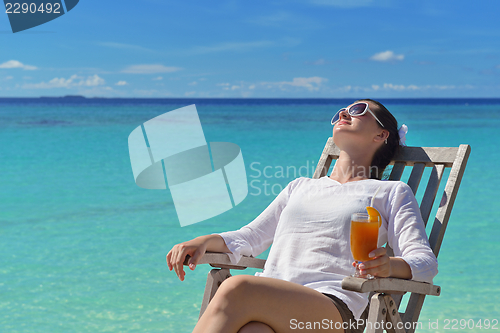 Image of Beautiful young woman with a drink by the sea