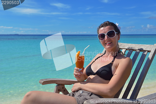 Image of Beautiful young woman with a drink by the sea