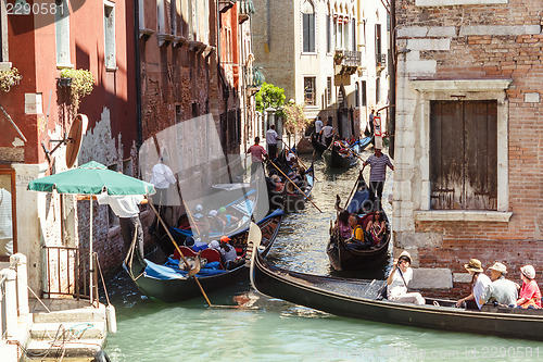 Image of ITALY, VENICE - JULY 2012: Heavy traffic of gondolas with tourists cruising a small canal on July 16, 2012 in Venice. Gondola is a major mode of touristic transport in Venice, Italy. 