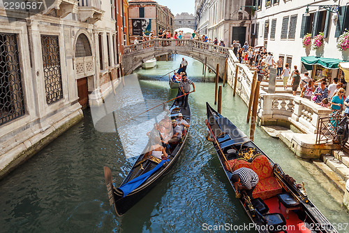 Image of ITALY, VENICE - JULY 2012: Gondolas with tourists cruising a small Venetian canal on July 16, 2012 in Venice. Gondola is a major mode of touristic transport in Venice, Italy. 