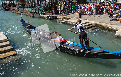 Image of ITALY, VENICE - JULY 2012: Gondolas with tourists cruising a small Venetian canal on July 16, 2012 in Venice. Gondola is a major mode of touristic transport in Venice, Italy. 