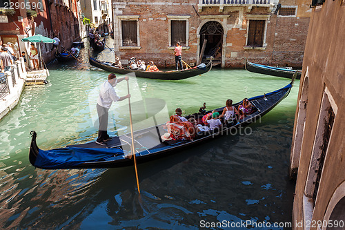 Image of ITALY, VENICE - JULY 2012: Heavy traffic of gondolas with tourists cruising a small canal on July 16, 2012 in Venice. Gondola is a major mode of touristic transport in Venice, Italy. 
