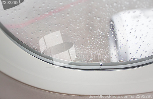 Image of Veritable rain drops on aircraft window and jet engine view