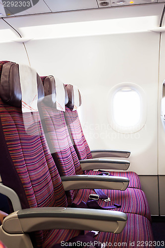 Image of Airplane seat row in passenger cabin with window beside 