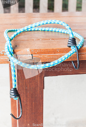 Image of Black hooks of blue rubber band on wood table 