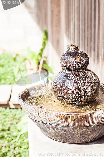 Image of Earthenware garden jar with water spring on sunlight 