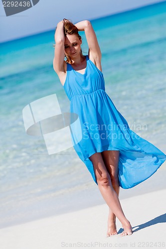 Image of beautiful woman in blue dress on beach in summer