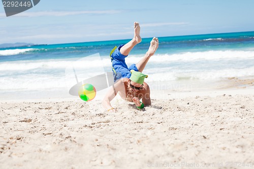 Image of attractive young man playing volleyball on the beach