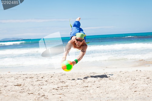 Image of attractive young man playing volleyball on the beach