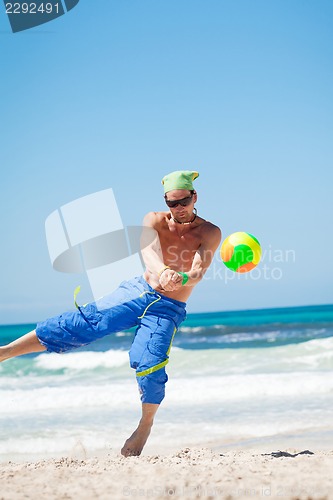 Image of attractive young man playing volleyball on the beach