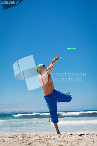 Image of attractive man playing frisby on beach in summer