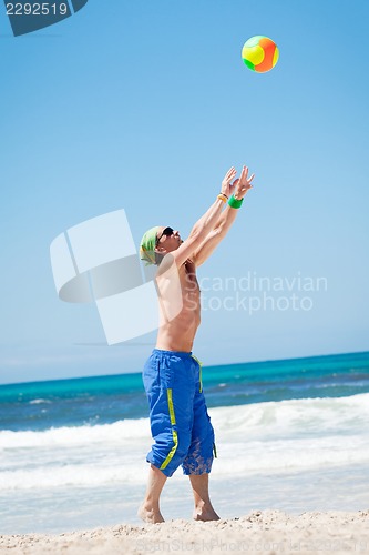 Image of attractive young man playing volleyball on the beach