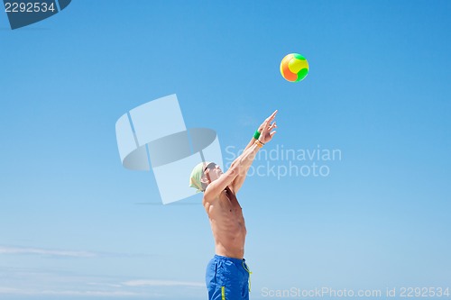 Image of attractive young man playing volleyball on the beach