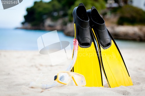 Image of yellow fins and snorkelling mask on beach in summer