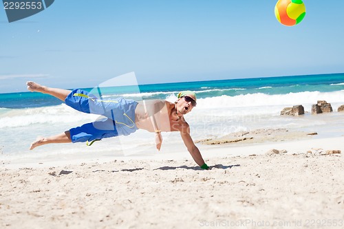 Image of attractive young man playing volleyball on the beach